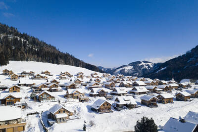 Luftaufnahme freistehender Ferienhäuser im Schnee im Alps Resorts Almdorf Hohentauern