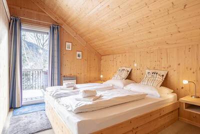 Doppelbett in einem Schlafzimmer eines Chalets im Alps Resorts Almdorf Stadl