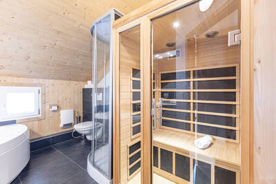 Badezimmer mit Badewanne, WC und Sauna in einem Ferienhaus im Alps Resorts Feriendorf Murau