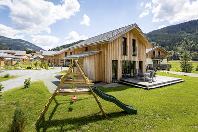 Kleiner Spielplatz neben einem Ferienhaus im Alps Resorts Feriendorf Murau