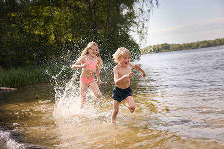 Kinder laufen durch das Wasser des Freizeitsees (Victoriameer) im Lake Resort Beekse Bergen