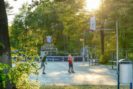 Kinder spielen Basketball auf dem Basketballplatz des Campingplatzes De Berenkuil