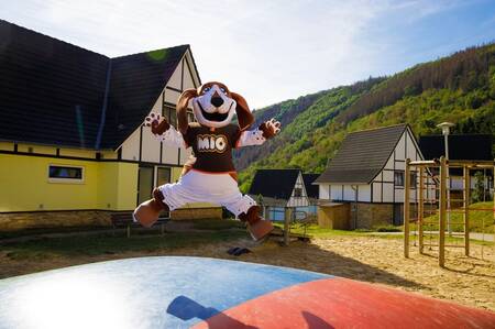 Maskottchen Mio springt auf dem Lufttrampolin auf einem Spielplatz im Ferienpark Dormio Eifeler Tor