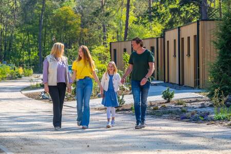 Familie geht an Ferienhäusern im Ferienpark EuroParcs Beekbergen vorbei