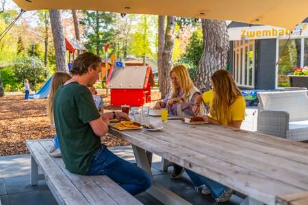 Die Familie isst Pommes auf der Terrasse des Restaurants im Ferienpark EuroParcs Beekbergen