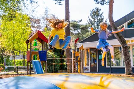 Kinder springen auf dem Lufttrampolin auf einem Spielplatz im Ferienpark EuroParcs Beekbergen