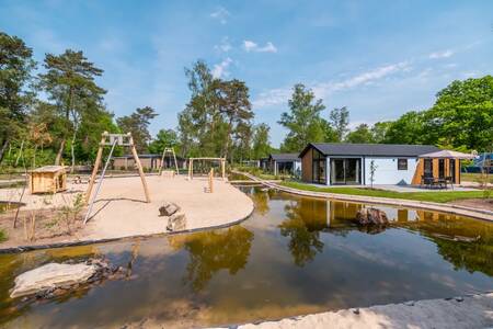 Spielplatz neben Wasser und Ferienhäusern im Ferienpark EuroParcs De Hooge Veluwe
