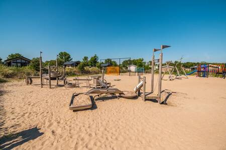 Spielgeräte auf einem großen Spielplatz im Sand im Ferienpark EuroParcs Poort van Zeeland