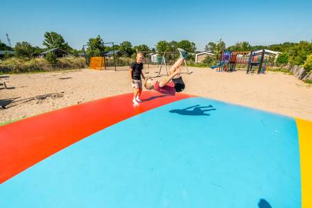 Kinder springen auf dem Lufttrampolin auf dem Spielplatz im Ferienpark EuroParcs Poort van Zeeland