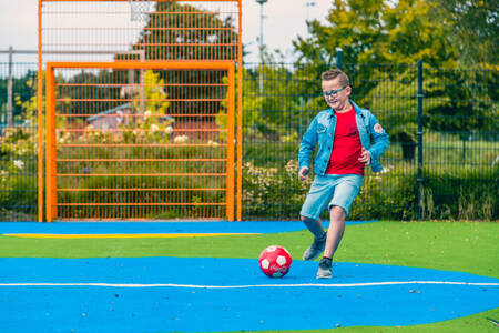 Junge spielt Fußball auf dem Spielfeld im Ferienpark EuroParcs Zuiderzee