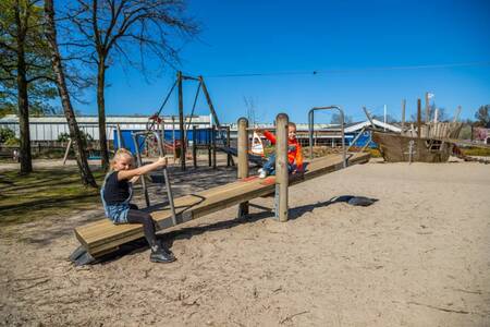 Kinder auf einer Wippe auf einem Spielplatz im Ferienpark EuroParcs Zuiderzee