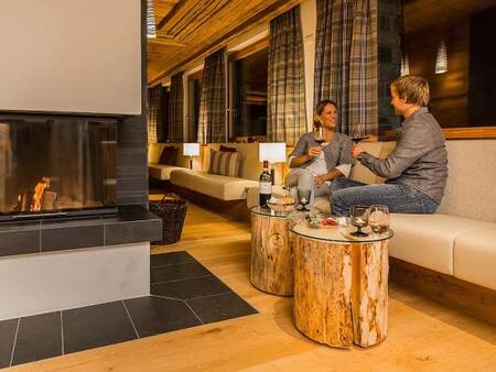 Paar genießt ein Glas Wein am Feuer in einem Restaurant der Landal Alpine Lodge Lenzerheide