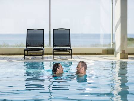 Ein Mann und eine Frau schwimmen im Schwimmbad von Landal Strandappartementen Fyrklit