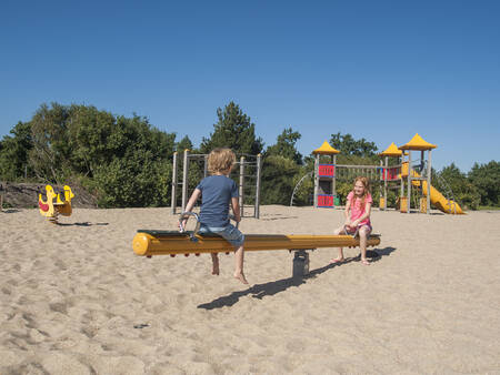 Wippe und Kletterausrüstung auf einem Spielplatz im Ferienpark Landal Beach Resort Ooghduyne