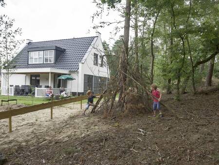 Kinder bauen eine Hütte im Wald neben einem Ferienhaus im Ferienpark Landal De Vers