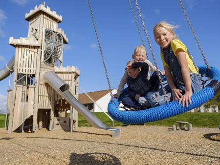 Kinder auf der Schaukel auf dem Spielplatz im Landal Vakantiepark Søhøjlandet