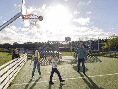 Die Familie spielt Basketball auf dem Spielfeld von Landal Vakantiepark Søhøjlandet