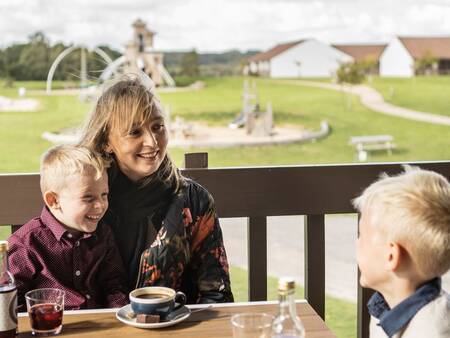 Die Familie genießt einen Drink auf der Terrasse der Brasserie im Landal Vakantiepark Søhøjlandet