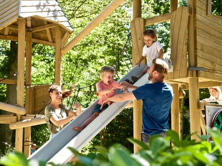 Die Familie spielt auf einem Holzspielplatz im Ferienpark Landal Heihaas