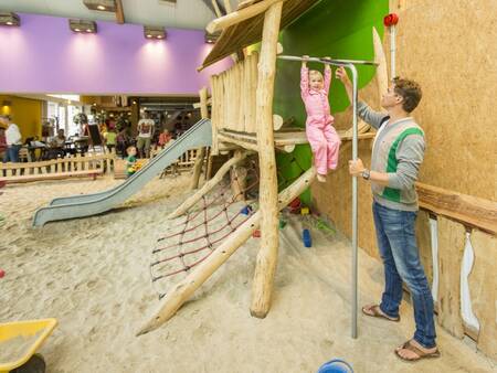 Vater und Kind spielen auf dem Indoor-Spielplatz des Ferienparks Landal Het Land van Bartje
