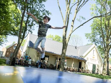 Kind springt auf dem Lufttrampolin auf dem Spielplatz des Ferienparks Landal de Waufsberg