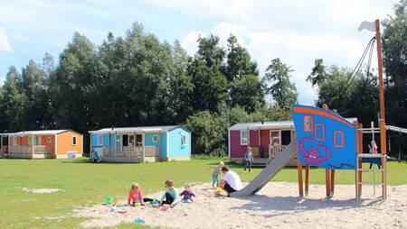 Chalets vom Typ "Pioen" auf einem Feld mit Spielplatz im Ferienpark Molecaten Park Flevostrand