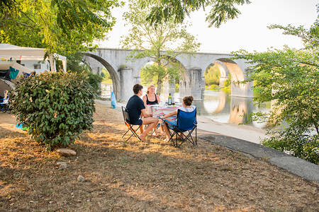 Im Ferienpark RCN La Bastide en Ardèche sitzen Menschen neben dem Fluss Ardèche