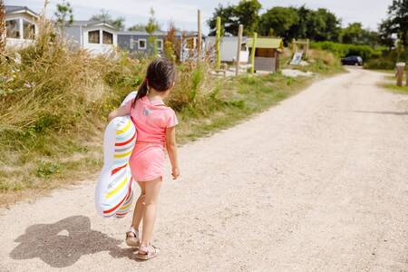 Mädchen geht einen Weg entlang, vorbei an Chalets im Ferienpark RCN Toppershoedje