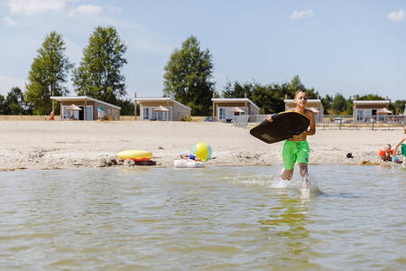 Junge läuft im Ferienpark RCN Zeewolde durch das Wasser des Veluwemeers