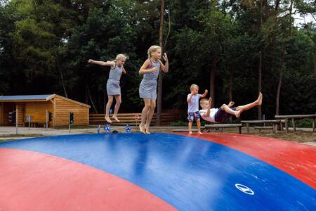 Kinder springen auf dem Lufttrampolin auf dem Spielplatz im Ferienpark RCN de Jagerstee