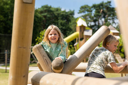 Kinder auf einem Holzspielplatz auf dem Spielplatz im Ferienpark RCN de Jagerstee