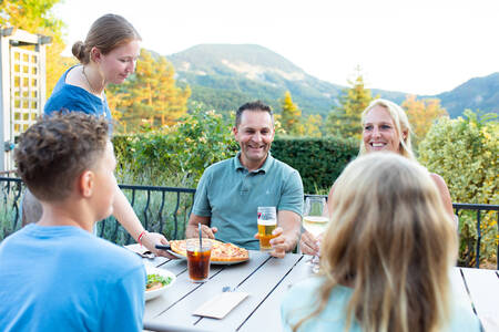 Familie isst auf der Terrasse des Bistros im Ferienpark RCN les Collines de Castellane