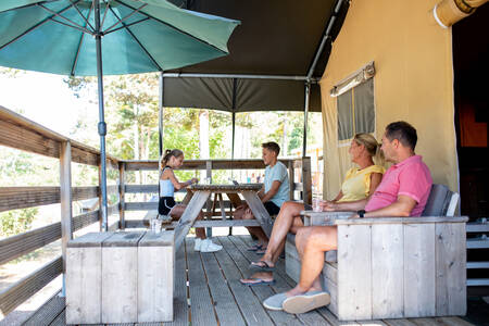 Die Familie sitzt auf der Veranda eines Safarizeltes im Ferienpark RCN les Collines de Castellane