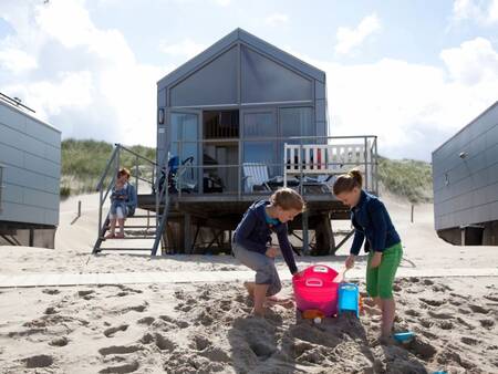 Kinder spielen im Sand vor einem Strandhaus im Roompot Strandhuisjes Julianadorp