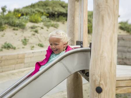 Kind auf der Rutsche auf dem Spielplatz von Roompot Beach Villas Hoek van Holland