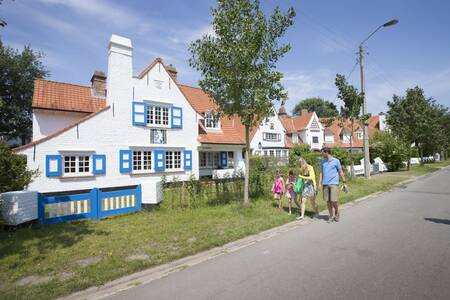 Eine Familie geht an Ferienhäusern im Ferienpark Roompot Breeduyn Village vorbei