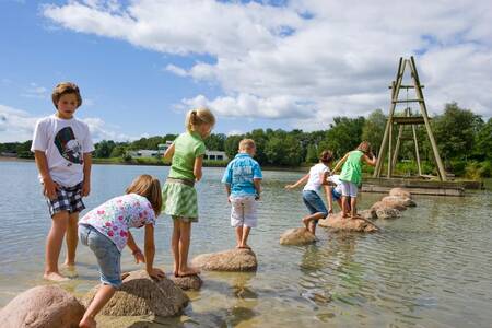 Kinder spielen auf Steinen im Erholungssee des Roompot Ferienparks Hunzedal