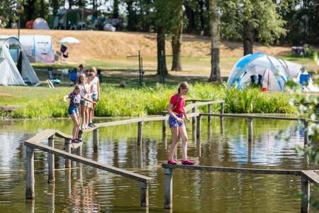 Kinder auf einem Schwebebalken über dem Wasser im Ferienpark Roompot Hunzepark