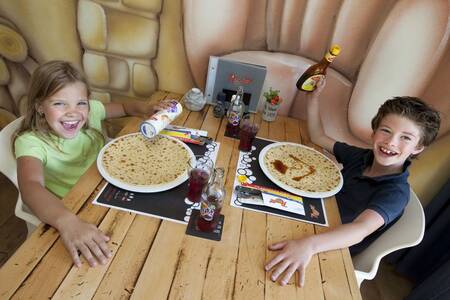 2 Kinder essen Pfannkuchen im Restaurant des Ferienparks Roompot Kustpark Egmond aan Zee