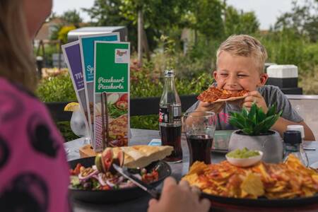 Die Familie speist auf der Terrasse eines Restaurants im Roompot Noordzee Résidence De Banjaard