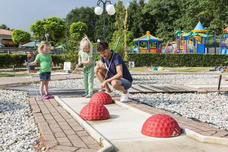 Kinder zusammen mit ihrem Vater auf dem Minigolfplatz des Ferienparks Roompot Resort Arcen