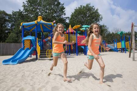Kinder toben auf einem Spielplatz im Ferienpark Roompot Resort Arcen