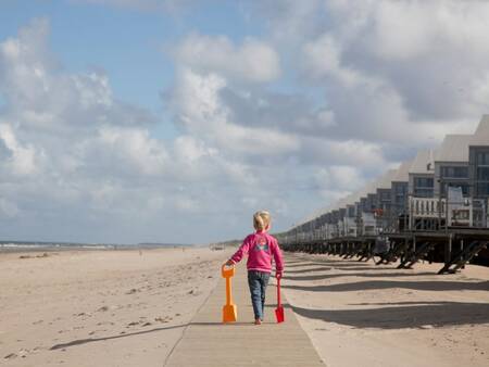 Kind geht am Strand vor den Strandhäusern von Roompot Strandhuisjes Julianadorp spazieren