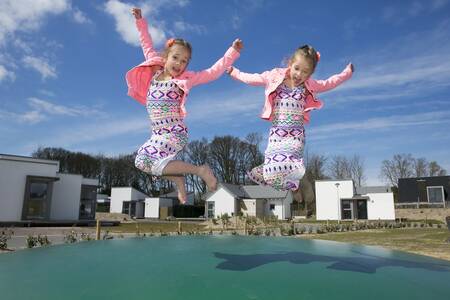 Kinder springen auf dem Lufttrampolin auf einem Spielplatz im Roompot Strandpark Duynhille