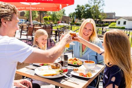 Familie beim Essen auf der Terrasse des Restaurants im Ferienpark Topparken Parc de IJsselhoeve