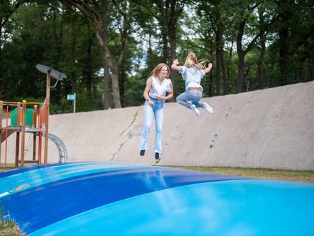 Kinder springen auf dem Lufttrampolin auf dem Spielplatz des Topparken Recreatiepark de Wielerbaan