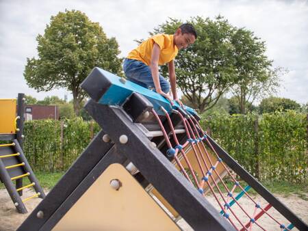 Junge klettert auf einem Spielplatz auf einem Spielplatz im Topparken Recreatiepark het Esmeer