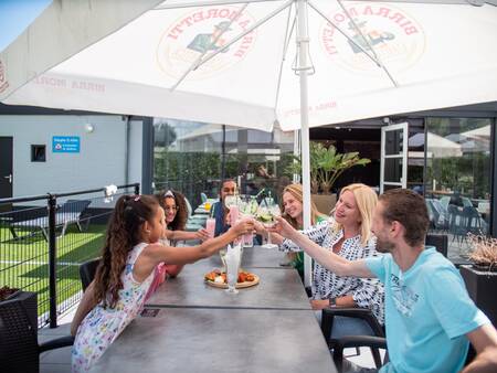 Die Familie genießt einen Drink auf der Terrasse des Restaurants der Topparken Résidence De Leuvert