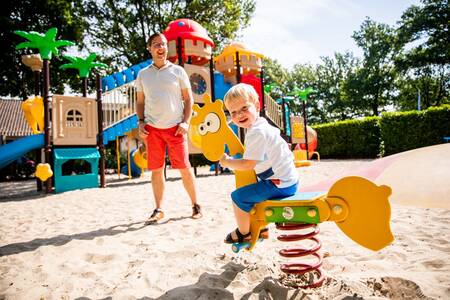 Kind auf einer Wippe auf einem Spielplatz im Ferienpark Topparken Résidence De Leuvert