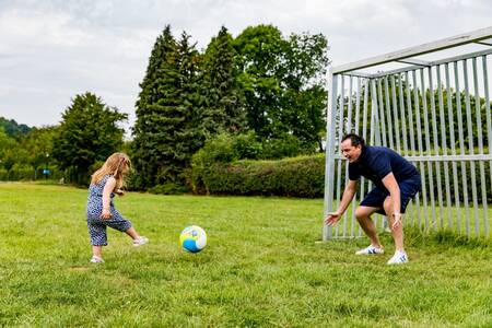 Vater und Tochter spielen Fußball auf dem Spielfeld des Ferienparks Topparken Résidence Valkenburg
